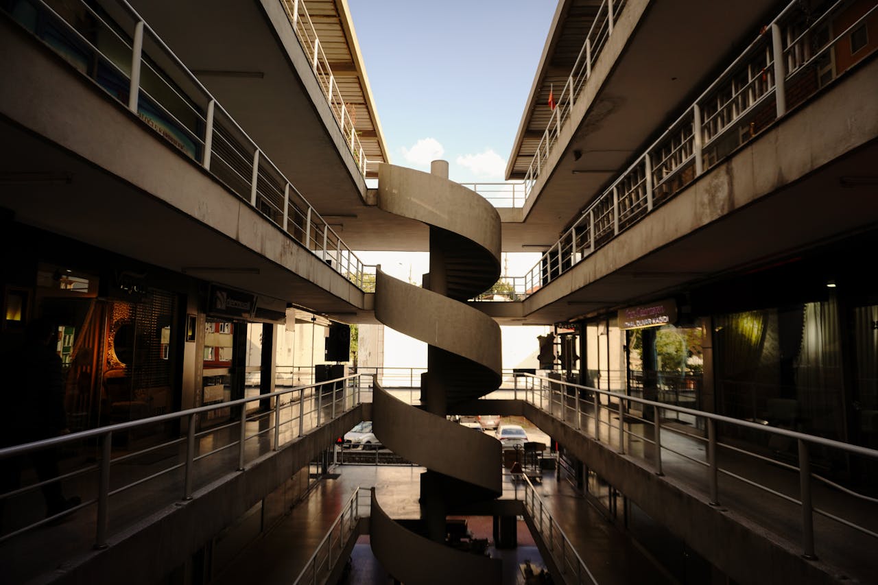 Interior view of a mall with a central spiral staircase and upper walkway levels.